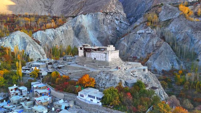 Aerial view of Baltit Fort perched atop a hill, surrounded by autumn colors and rugged mountains, Karimabad, Gilgit Baltistan, Pakistan.