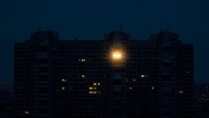 A tall building stands illuminated at dusk with street light shining brightly beside it
