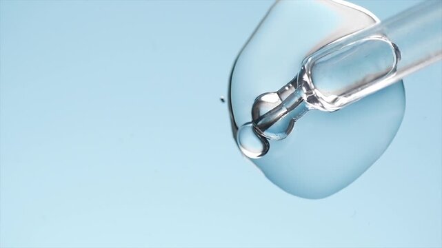 Cosmetic dropper, glass pipette with serum, beauty cosmetics dripping, on blue background. Science. Serum, peptides, beauty and health care products. liquid enzymes close up. Top view. Skin care