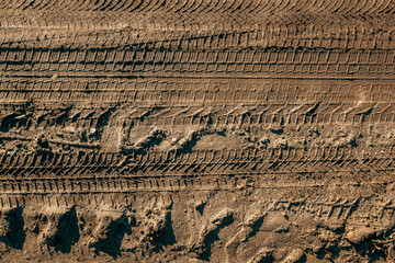 Texture of deep, detailed truck tire tracks pressed into cracked, dry mud.