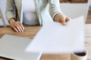 Shot of an unrecognisable businesswoman handing a document at her desk in a modern office.