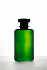 Shampoo or lotion bottle with a black dispenser ang green bright liquid , standing out against a stark white background.