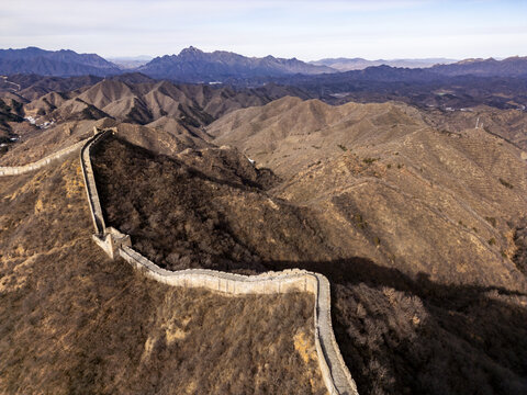 Aerial view of the Great Wall snaking through the rugged, mountainous terrain, a stone dragon against the ochre landscape, Jingshanling, Beijing, China.