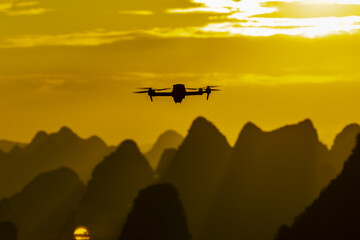 View of a drone soars against a vibrant sunset backdrop, casting long shadows over the majestic, undulating peaks, Xingping, Guillin, China.