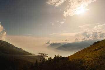 spectacular backlight of a mountain landscape from above with chairlift and surreal clouds and fog...