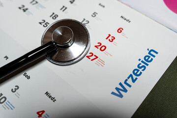 A close-up view of a doctor's stethoscope placed on a calendar page of September, highlighting important dates and events, symbolizing health management and planning.