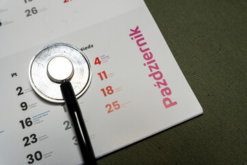 A close-up of a calendar page for October with a stethoscope laying on top. The calendar features important dates and a clean, organized layout, ideal for healthcare discussions.