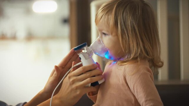 A loving mother assists her young daughter with a nebulizer treatment for a respiratory issue. With the aerosol device, she provides comforting care to alleviate cough and asthma symptoms