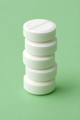 Stack of white pills on green background