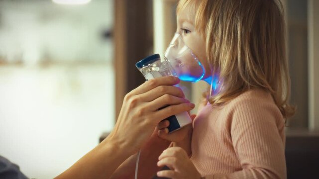 Caring mother assists her child with aerosol inhalation treatment using nebulizer, carefully holding mask to their face. As educator and mentor, she guides the process for the child's asthma relief
