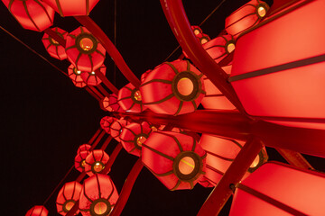 View of vibrant red lanterns glow warmly against the inky black sky, suspended on curved metal structures, creating a festive atmosphere, Xi'An, Shaanxi, China.