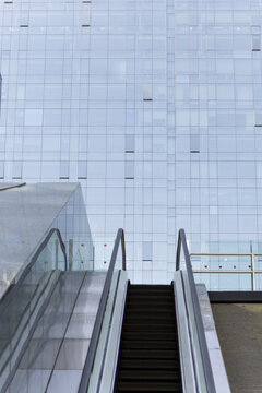 View of the modern architecture with sleek escalators leading to a glass-clad building reflecting the sky, creating a contrast of textures, Xi'An, Shaanxi, China.