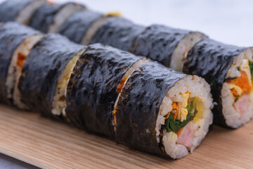 Fresh Korean gimbap rolls sliced and neatly arranged on a wooden board, showing colorful ingredients and a clean, appetizing food presentation.