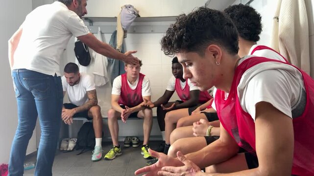 Coach giving pep talk to basketball team in locker room