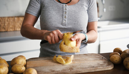 Woman Peeling Raw Potatoes And Vegetables With A Knife