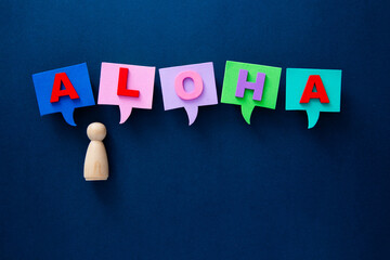 Wooden figure communicating aloha greeting using colorful speech bubbles