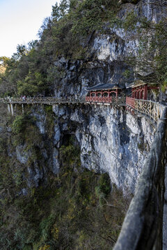 View of ancient architecture clinging to the edge of a sheer cliff face, a testament to human endeavor against nature's grandeur, Zhangjiajie, hunan, China.