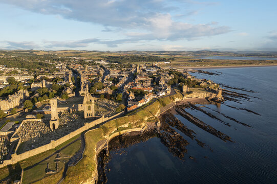 Aerial view of the golden coastline meeting the deep blue sea near the historic St Andrews Cathedral ruins, St Andrews, Scotland, United Kingdom.