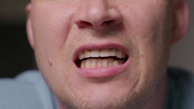 Close up of a man chattering his teeth with visible jaw movement. Focus on mouth and teeth without full face, showing a natural physical reaction and facial motion detail. High quality 4k footage