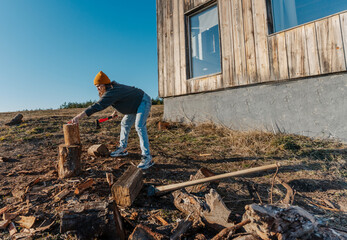 Young woman chopping wood in a country house in the wilderness, winter heating fireplace concept