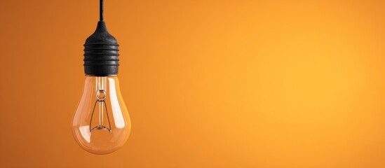 A light bulb hanging on a black cord against an orange gradient background