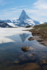 Vertical landscape of Matterhorn mountain with reflection on melting frozen lake in Zermatt, Switzerland