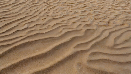 Close-up shot of rippling sand dunes creating a beautiful abstract pattern of light and shadow