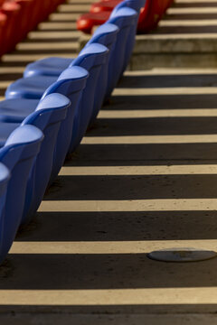 View of vibrant red and blue stadium seats ascending in rhythmic order, casting stark shadows across the steps, creating a captivating visual symphony, Beijin, Beijin, China.