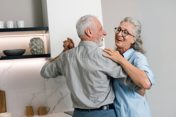 Senior couple dances happily at home during weekend together