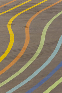 View of vibrant waves of yellow, orange, green, and blue paint ripple across the textured gray ground, creating a playful, abstract landscape, Beijing, Beijing, China.