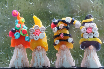 Figures of dwarfs made of plasticine on the background of a wet window.