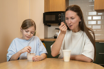 Mother and daughter sharing a meal at a kitchen table, enjoying breakfast together in a modern home environment, reflecting family bonding and a healthy routine