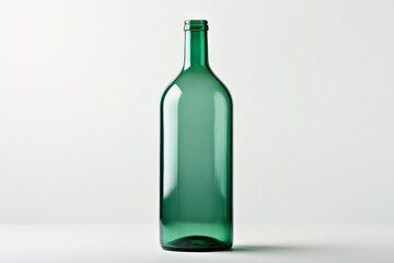 Empty green glass bottle standing on a white background, creating a minimalist and elegant composition