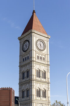 View of the old clock tower under the clear sky with its brick-red roof contrasting against the beige stone facade, Tianjin, Tianjin, China.