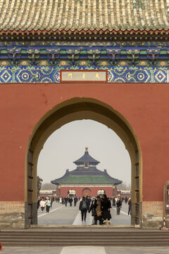 View of a captivating archway framing the Temple of Heaven, adorned with intricate blue and green detailing, under a muted sky, Beijing, Beijing, China.