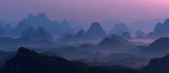 Serene landscape of layered, misty mountains at dusk, bathed in purple and blue hues