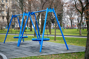 Empty swings on a playground in a city park in winter