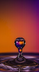 Water droplet splashing on surface with colorful gradient background  