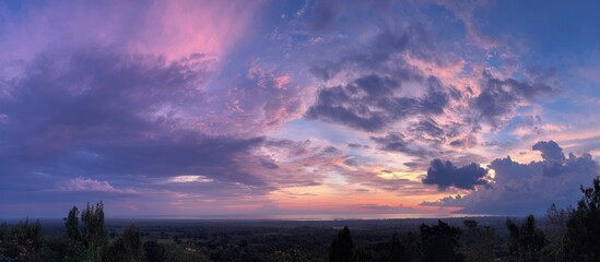 Panoramic dusk scene. Pink, purple, and blue clouds dominate sky, overlooking a dark landscape