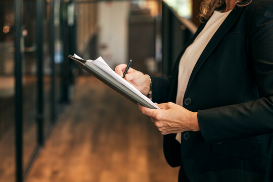 Midsection of female business professional writing on document while working in law firm