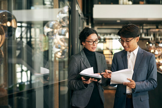 Male and female business experts discussing documents with each other in law firm