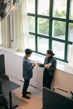 High angle view of male and female business experts discussing documents with each other in law firm