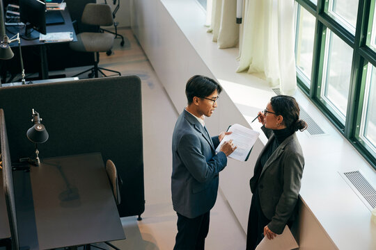 High angle view of female business expert discussing documents with male colleague in law firm