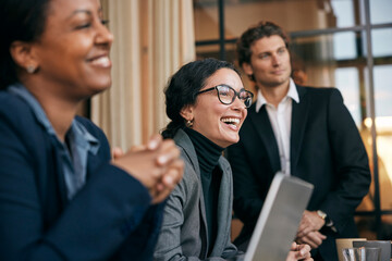 Happy female business professional enjoying while sitting with colleague in meeting at law firm