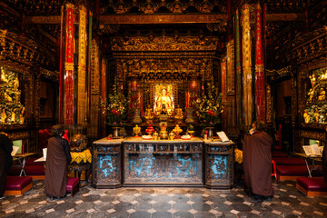 Taipei City, Taiwan - 11 April 2025: View of Longshan Temple's vibrant interior, where golden statues gleam amidst intricately carved wood and softly lit ceremonial objects.