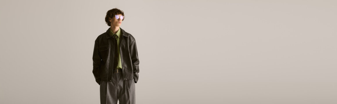 Stylish young man stands confidently in a modern urban setting showing off unique fashion