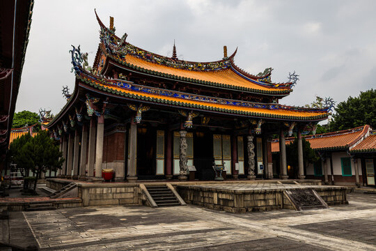 Taipei City, Taiwan - 11 April 2025: View of the ornate Baoan Temple under a cloudy sky, its intricate roof details a stark contrast to the stone courtyard below.