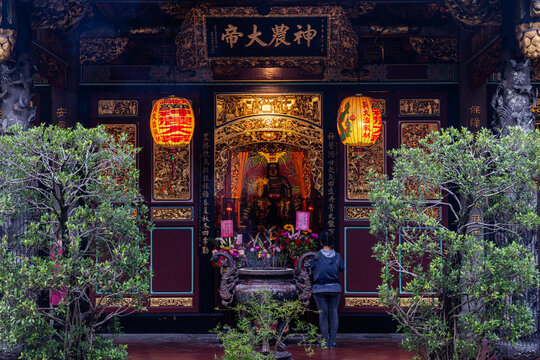 Taipei City, Taiwan - 11 April 2025: View of the ornately carved Baoan Temple entrance glows warmly, framed by lush greenery and softly lit lanterns.
