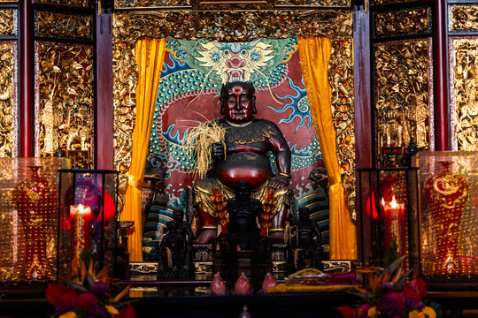 Taipei City, Taiwan - 11 April 2025: View of a red-faced deity enthroned in the Baoan Temple, framed by golden carvings and vibrant yellow drapes, a scene of spiritual opulence.