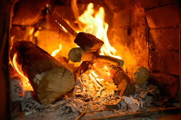 Wood logs burning brightly inside a rustic brick fireplace, creating intense flames and glowing embers that symbolize warmth, comfort, and a cozy atmosphere